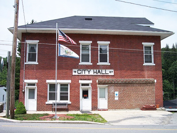 The American flag above the State of West Virginia flag in front of a city hall in West Virginia