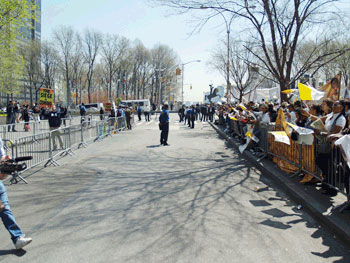 protestors holding signs critical of the Catholic Church; on the other side of the street counter protestors hold signs in support of the Catholic Church; police patrol the street between them