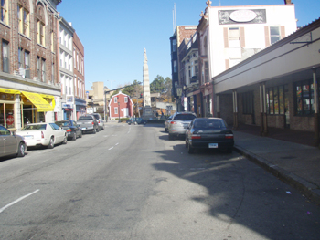 downtown street  in New London, Connecticut with storefronts on each side of the road; barn in the background