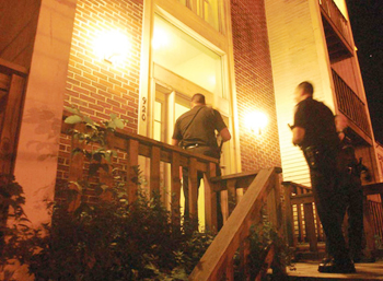 two officers standing at a doorway of a townhouse at night