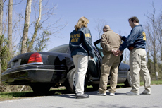 two federal officers arresting a suspect and putting him in a police car