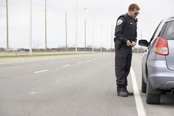 Officer talking to a driver through the car window on a highway