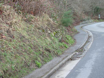 a sidewalk under a steep hill