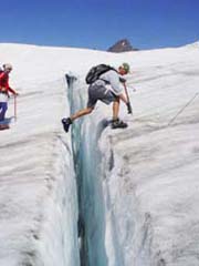 hikers crossing a crevasse in a glacier