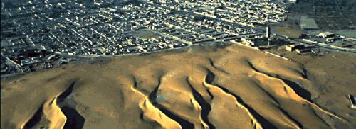 sand dunes migrating toward a town