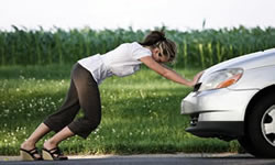 A woman pushing a stalled car