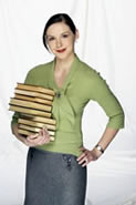 A woman holding a huge pile of books