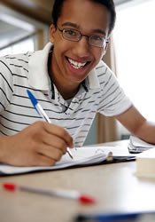 A teen boy writing.