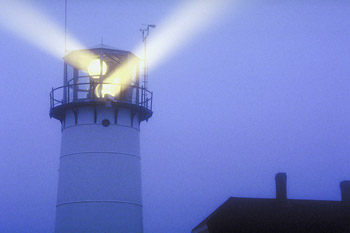 A lighthouse in the fog with two beams of light emanating from the top