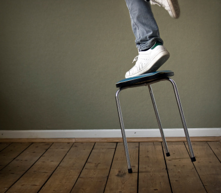 person on a unstable stool about to fall