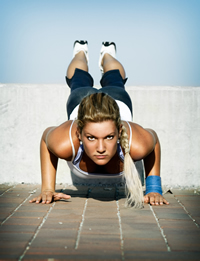 A young lady doing push-ups outdoors on a sunny day; iStock.com