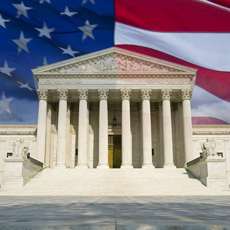 The front of the U.S. Supreme Court in Washington D.C with the U.S. flag in the background.