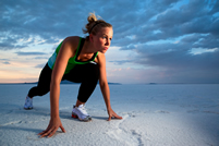 A female exercising on a beach; iStock.com