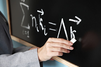 A teacher writing a math equation on the chalkboard; Shutterstock.com