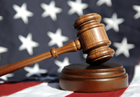 Judge's Wooden Gavel with flag in background; Shutterstock.com