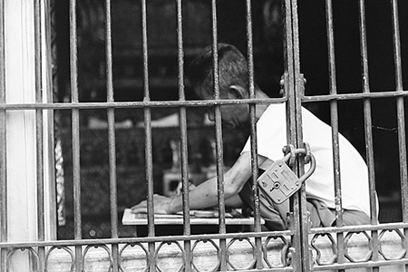 Man in jail cell, writing.