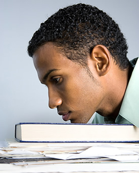 Stressed-looking man with his head on a pile of books