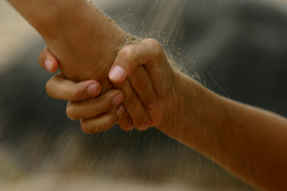 Two hands clasped in a supportive gesture