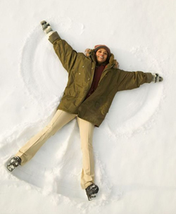 Woman lying in the snow making a snow angel