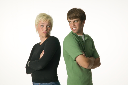 Young man and young woman standing back to back